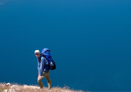 Erick descending steep slopes towards a deep, blue, unnamed lake.