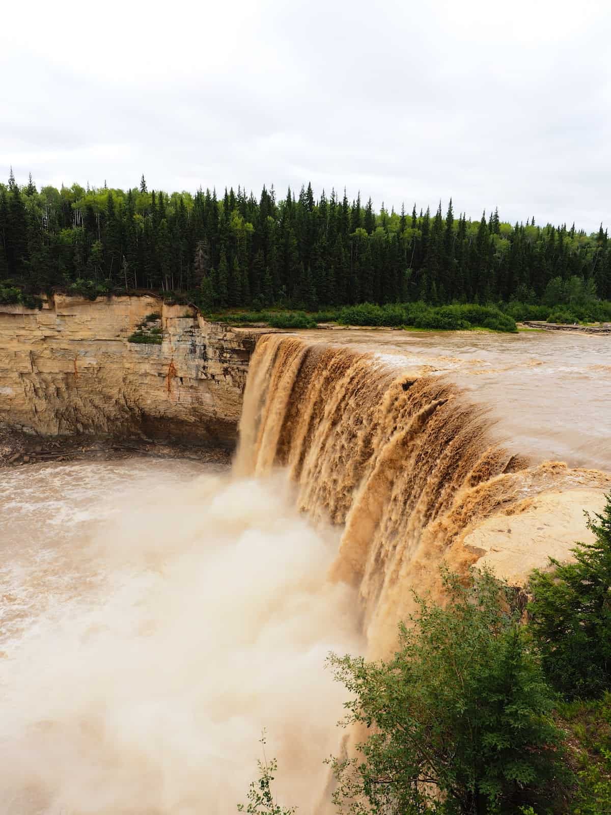 Nahanni River by Canoe: A muddy river crests over a waterfall