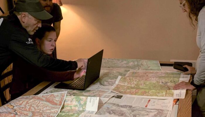 hikers planning a backpacking trip with maps and a computer