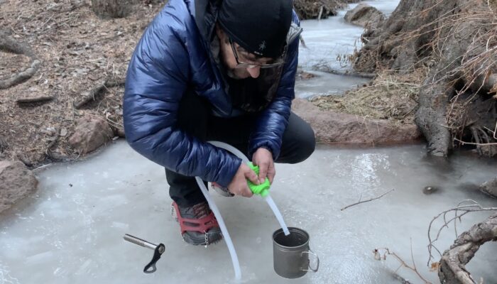 ryan using a suction tube to get water out of a frozen creek