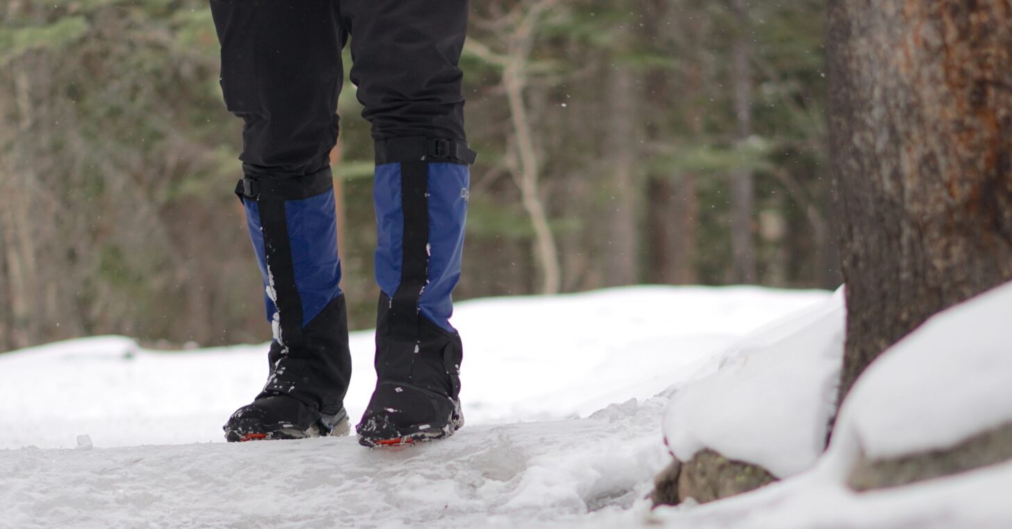 person standing on an icy trail wearing traction spikes