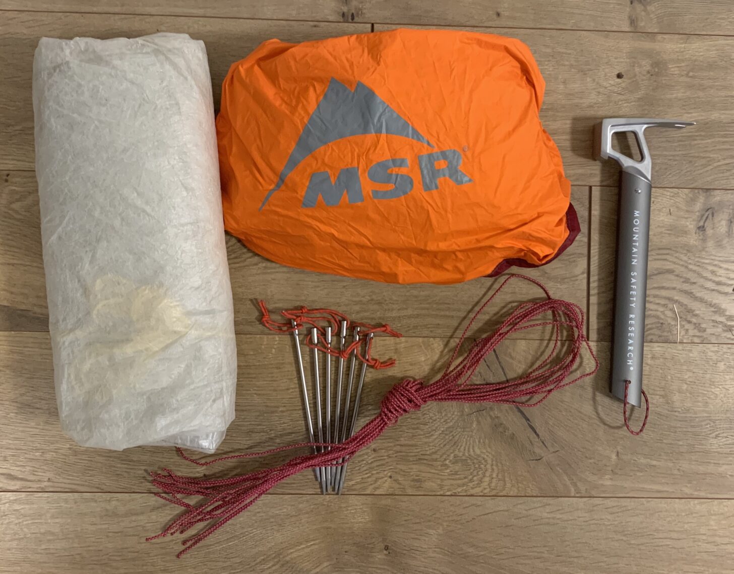 tarp, bivy sack, nail stakes, extra guylines, and a stake hammer