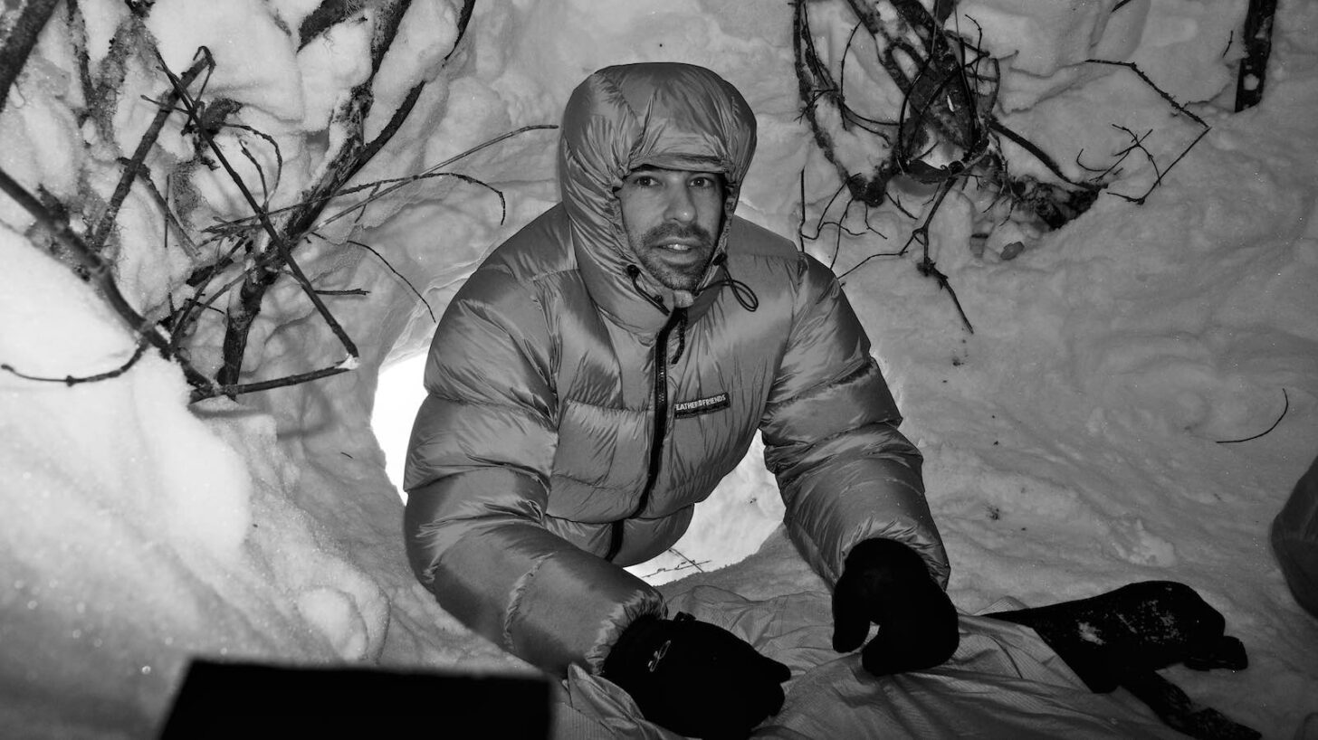 person wearing down parka inside a snow cave