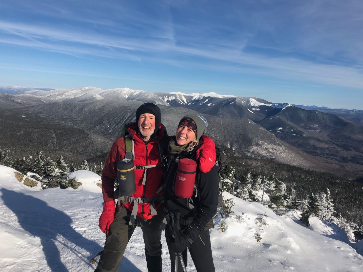 a father and daughter stand side by side on top of a mountain