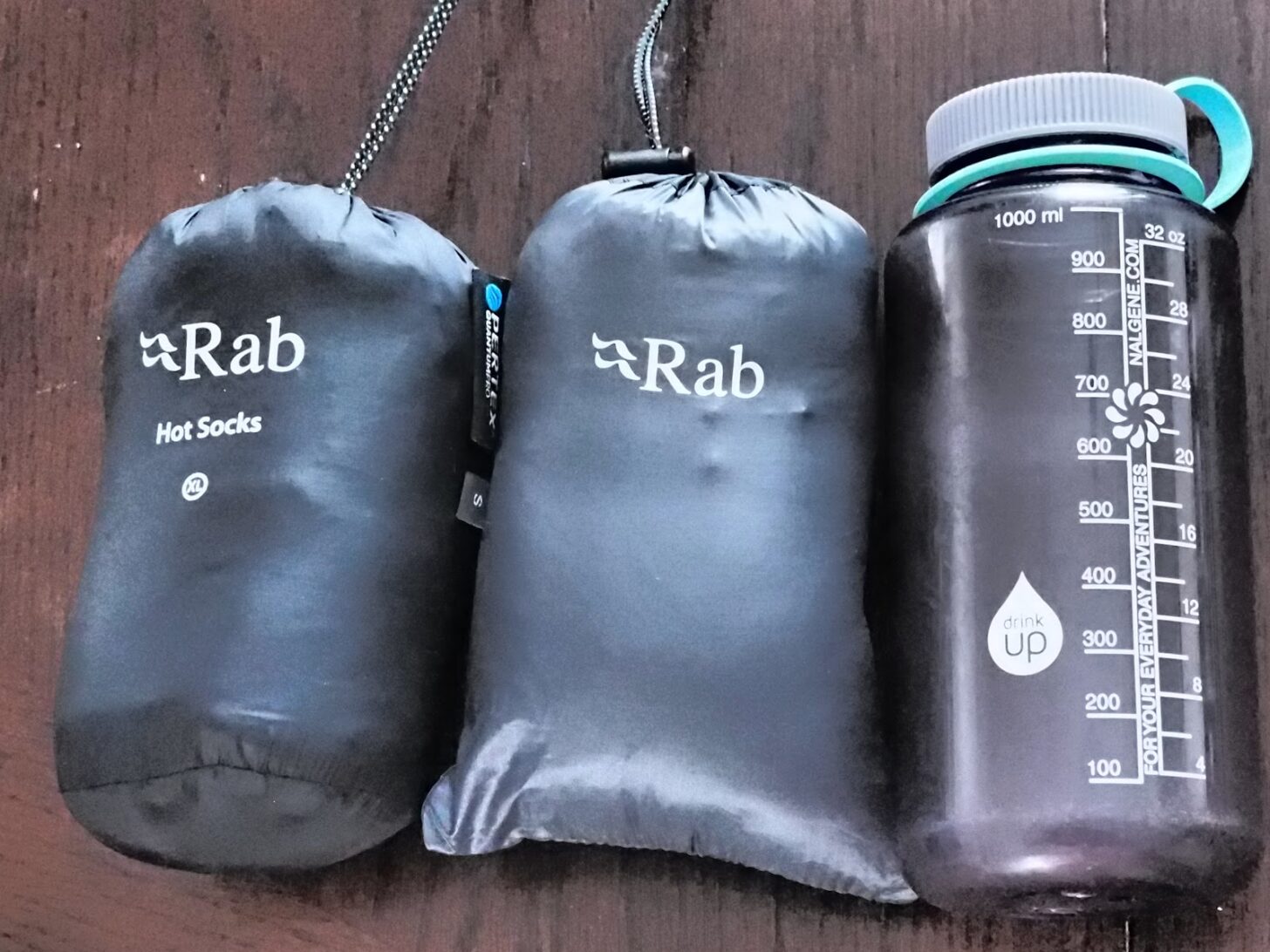 Both products in stuff sacks next to a water bottle for comparison