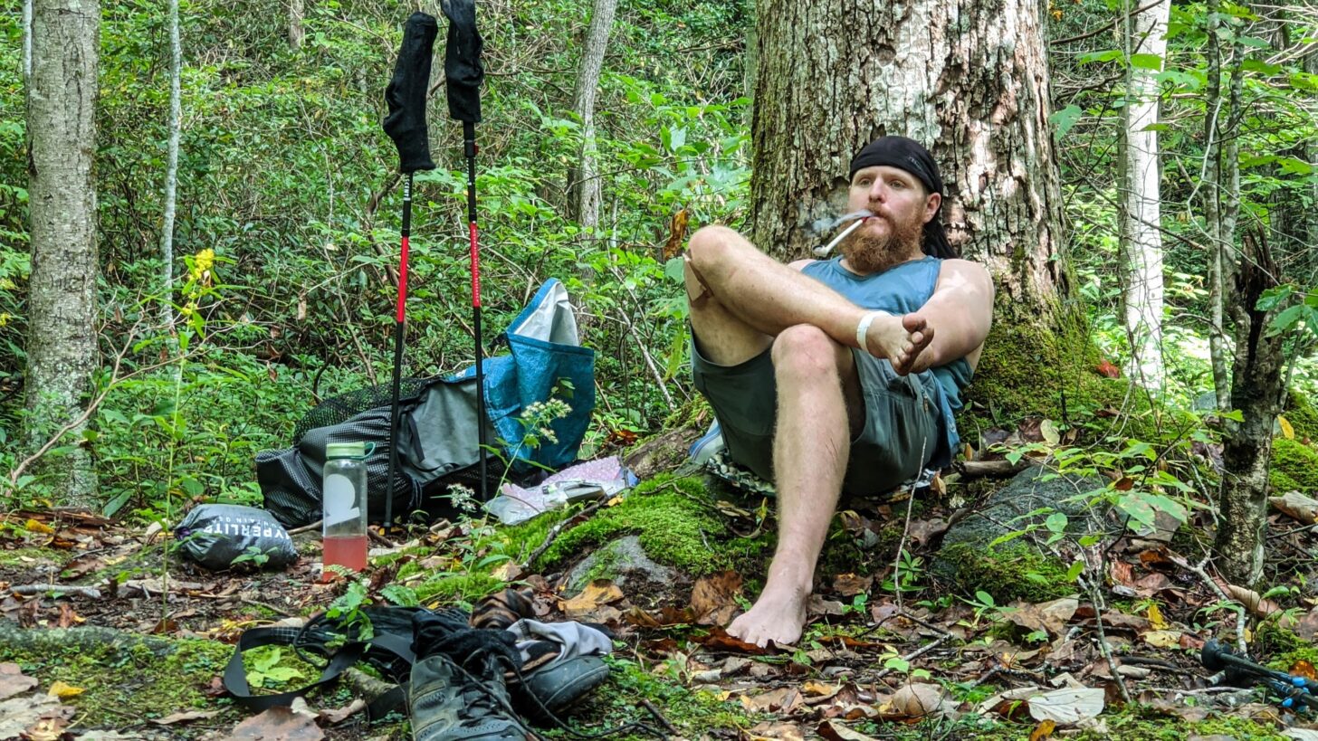 a man sits on a sit pad in the middle of the woods