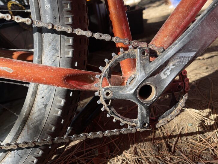 the chain, front crank, and tire of a bicycle