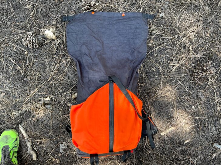 a medium shot showing the pack on the ground with the roll-top compartment fully unrolled.