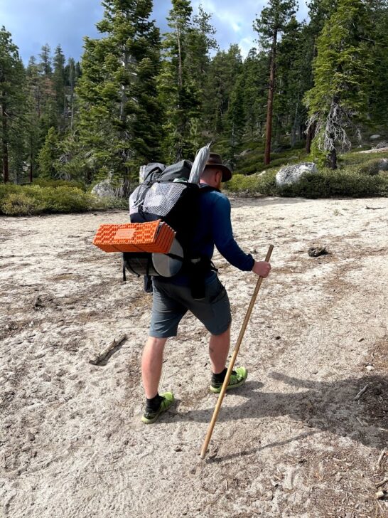 A medium-wide shot of a man hiking up a slight incline wearing the pack.