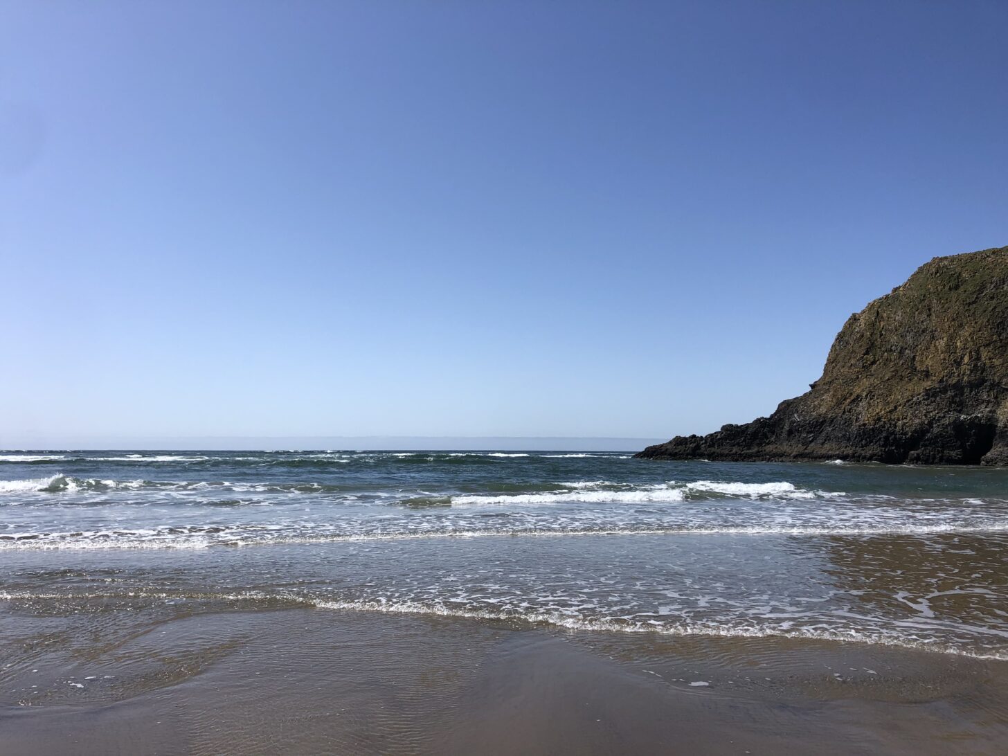 a beach landscape with steep cliffs in the right hand side of the frame.