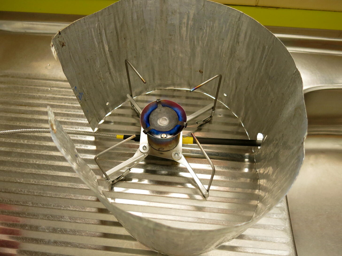 a stove inside a wind screen on a workbench