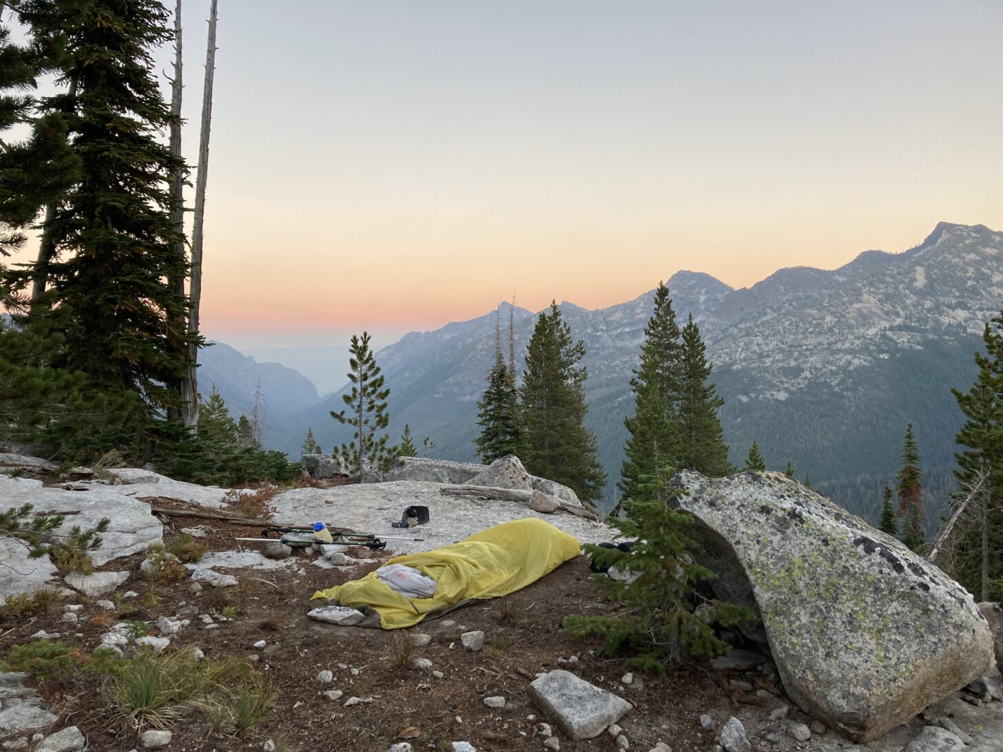 a campsite looking out over a range of mountains and a canyon, with a haze of fog or smoke in the background