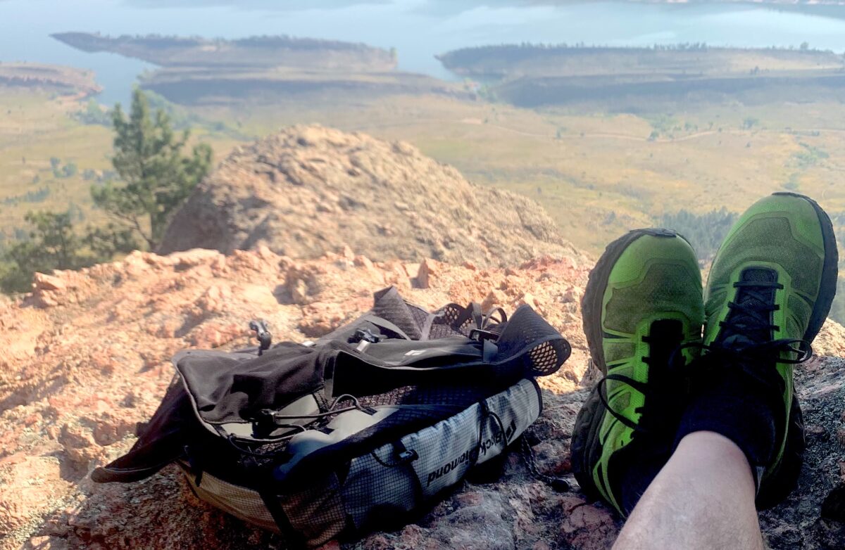 hiker wearing trail running shoes with a backpack on a mountain with a view