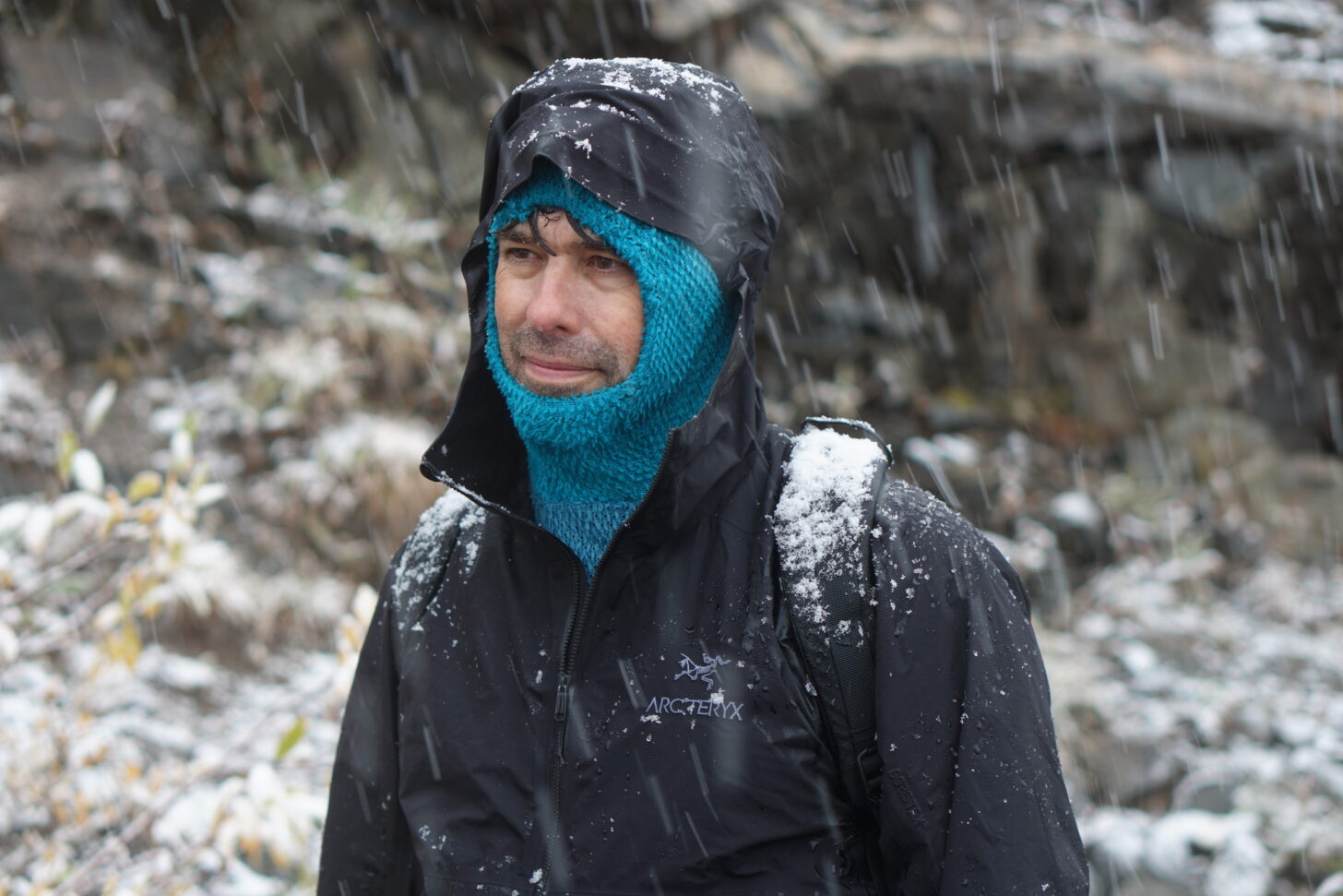 man wearing a polartec alpha direct hoody under a hardshell