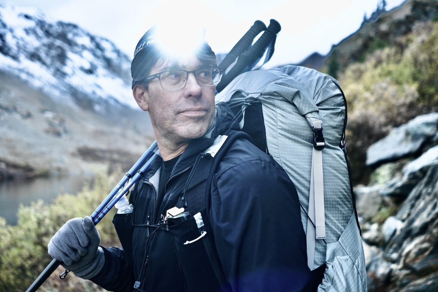 hiker wearing a pack and using trekking poles.