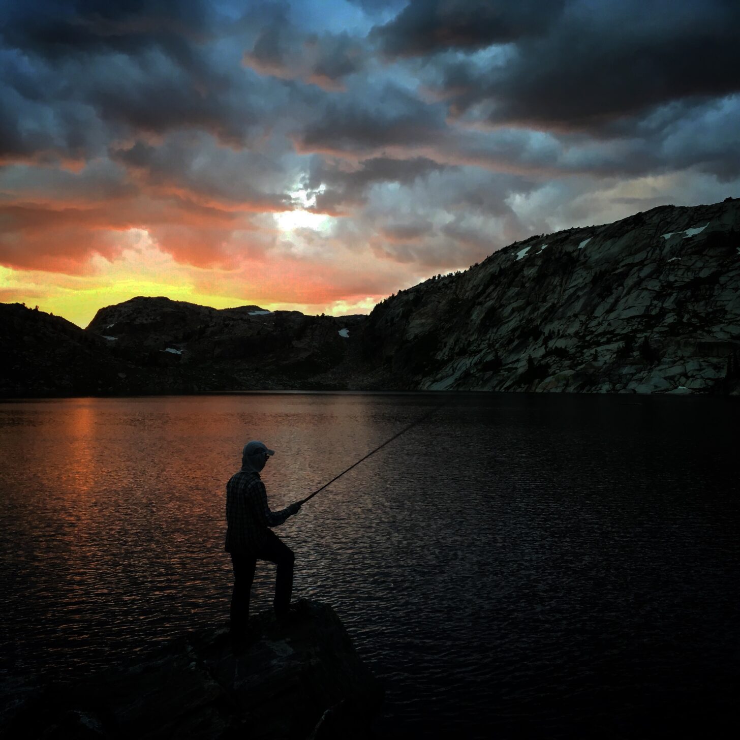fishing at an alpine lake at sunset