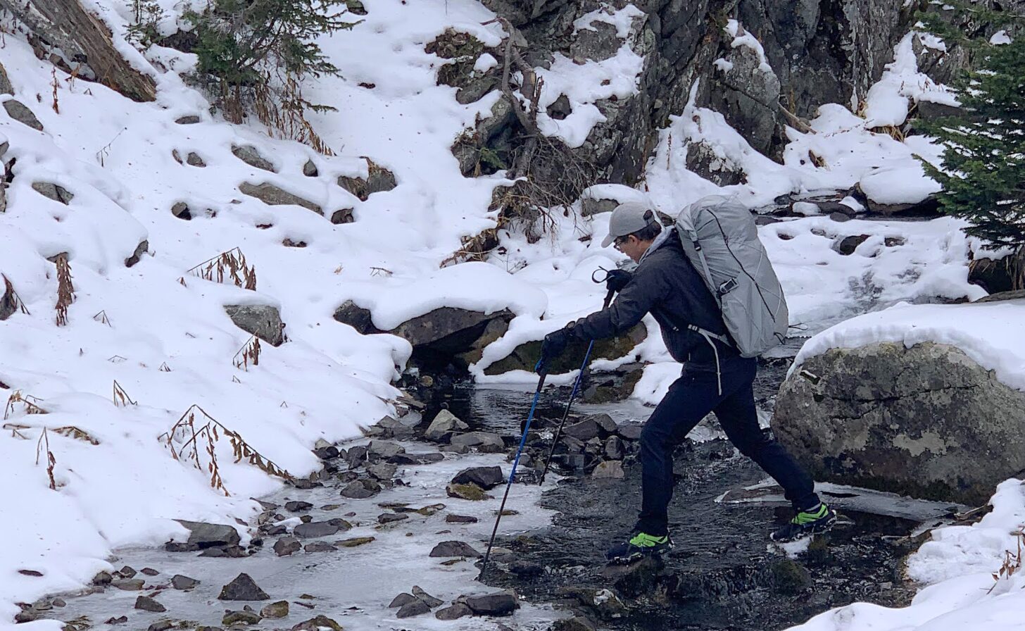 hiker crossing an icy creek