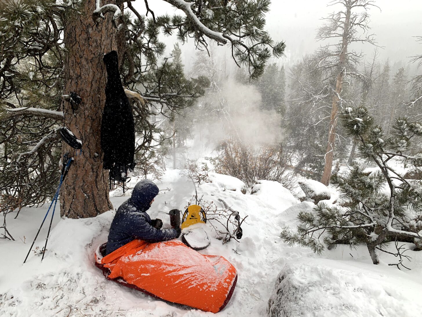 hiker camping in a bivy sack in a snowy forest, cooking on a stove