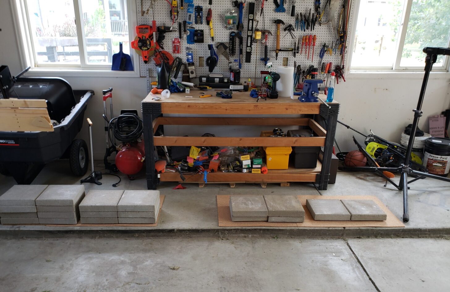 The author's garage with testing gear set up to test synthetic insulation degradation. From the bottom up: Cork pad, Rip-stop fabric, Insulation Sample, Rip-stop fabric, cork sheet, concrete pavers. As can be seen, for each sample, insulation is completely crushed under the weight of the pavers.