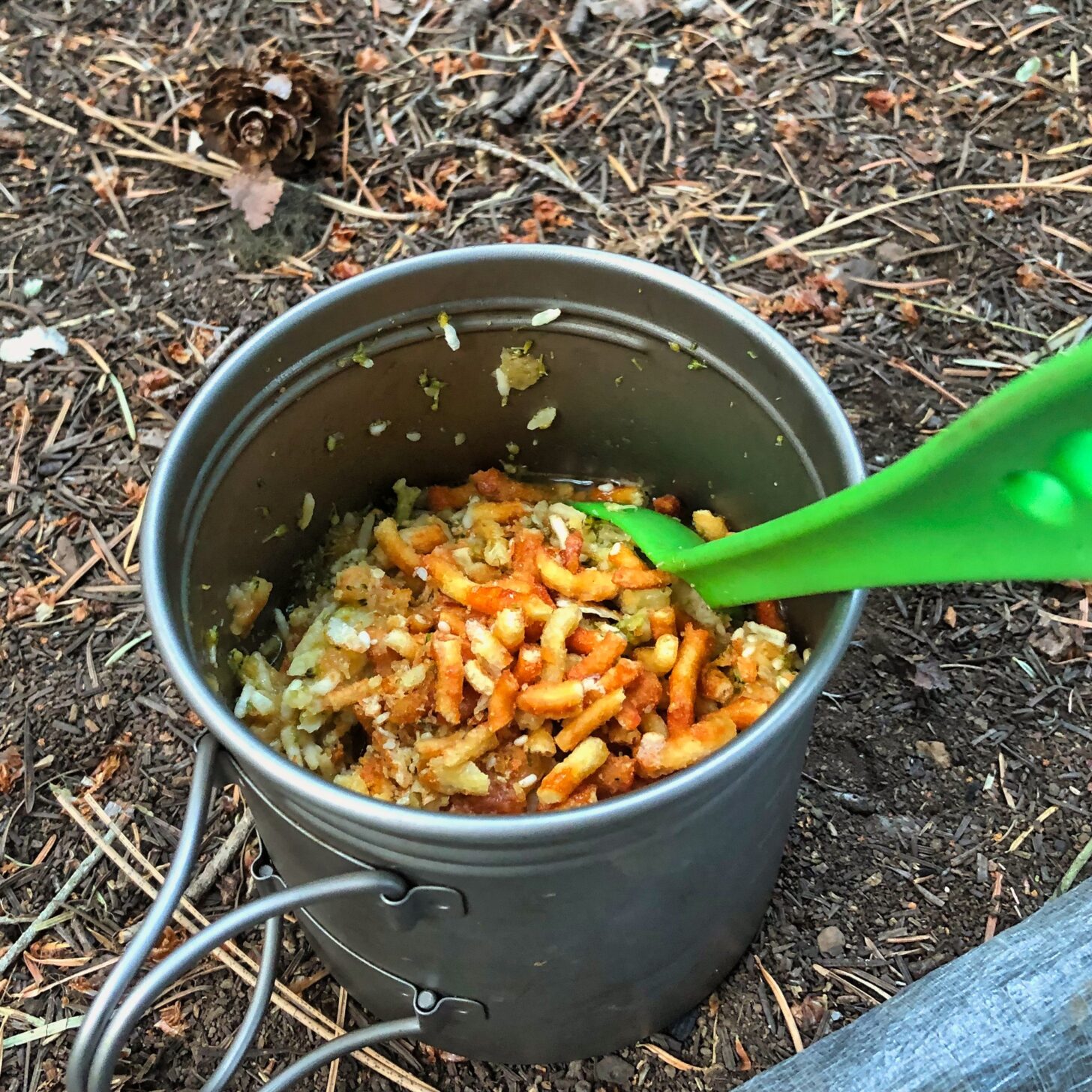 a pot with asian food in it and a green spoon sticking out of it.