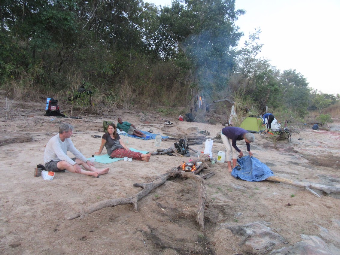 a group of hikers lounge along a riverbank