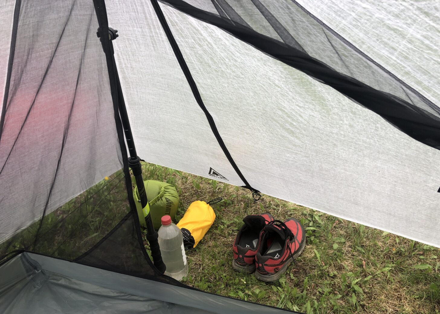 Shoes, a water bottle, and two small items are shown under a tent vestibule.