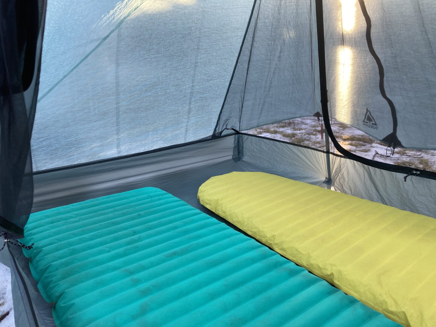 Two sleeping pads are shown inside a tent.