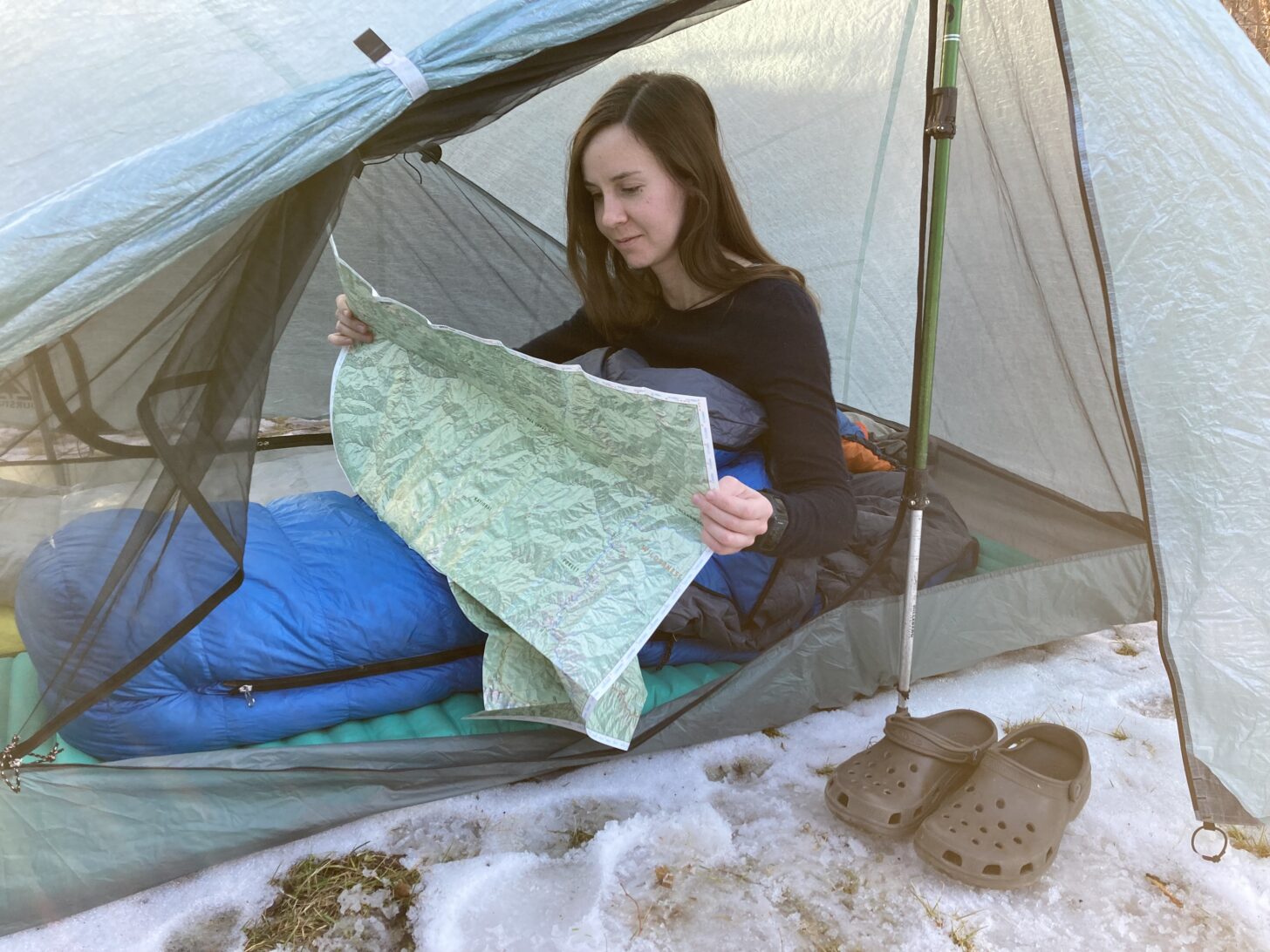 A woman reads a map inside a tent.