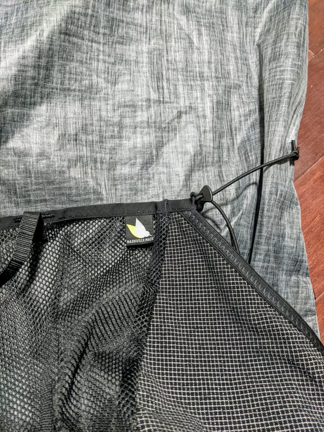 A close up of a cord running from the side of the Nashville Pack Cutaway backpack to the top corner of a pocket