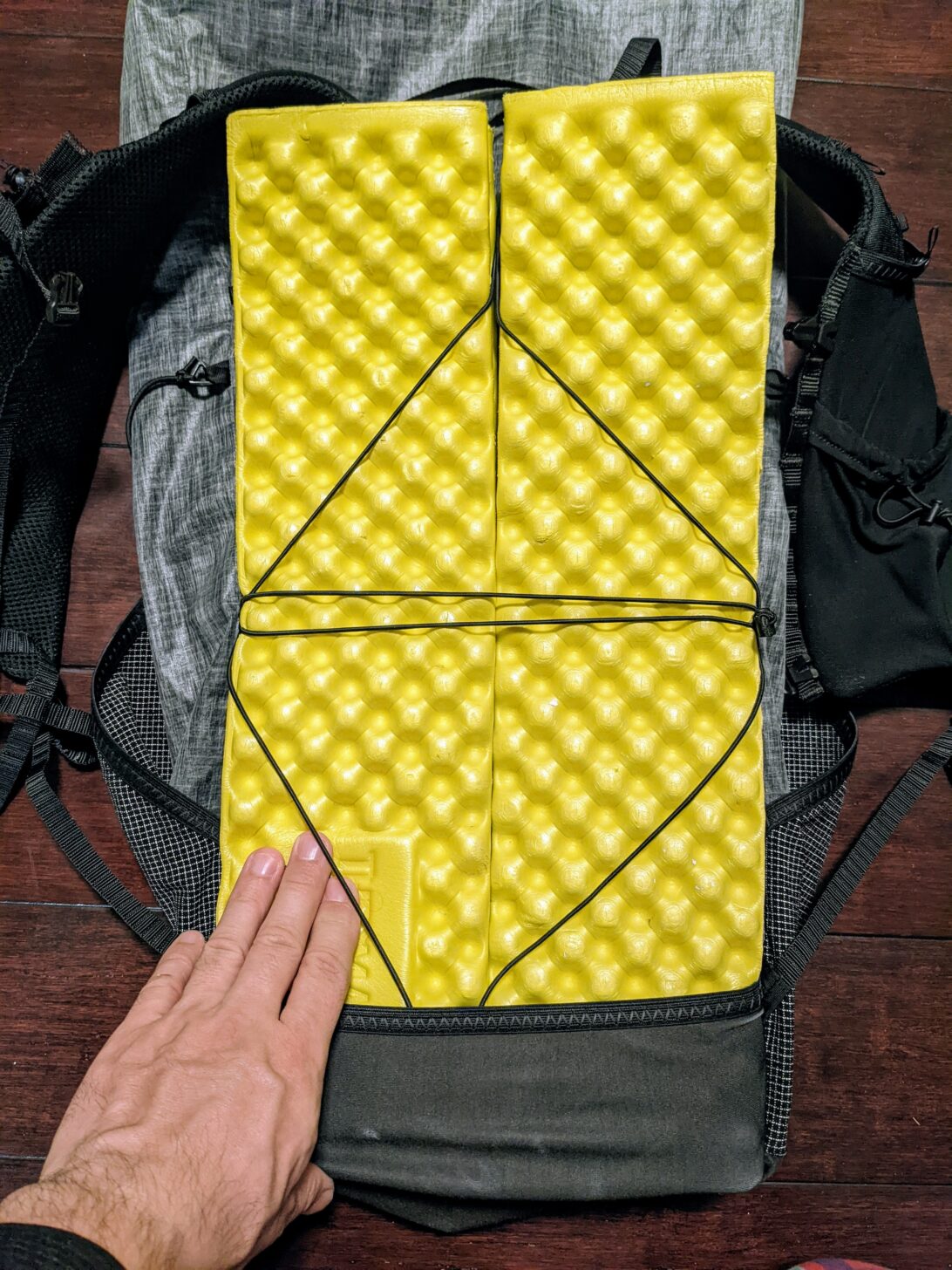 A shot from above looking down at the back of the Nashville Pack Cutaway backpack with a yellow sleeping pad attached.