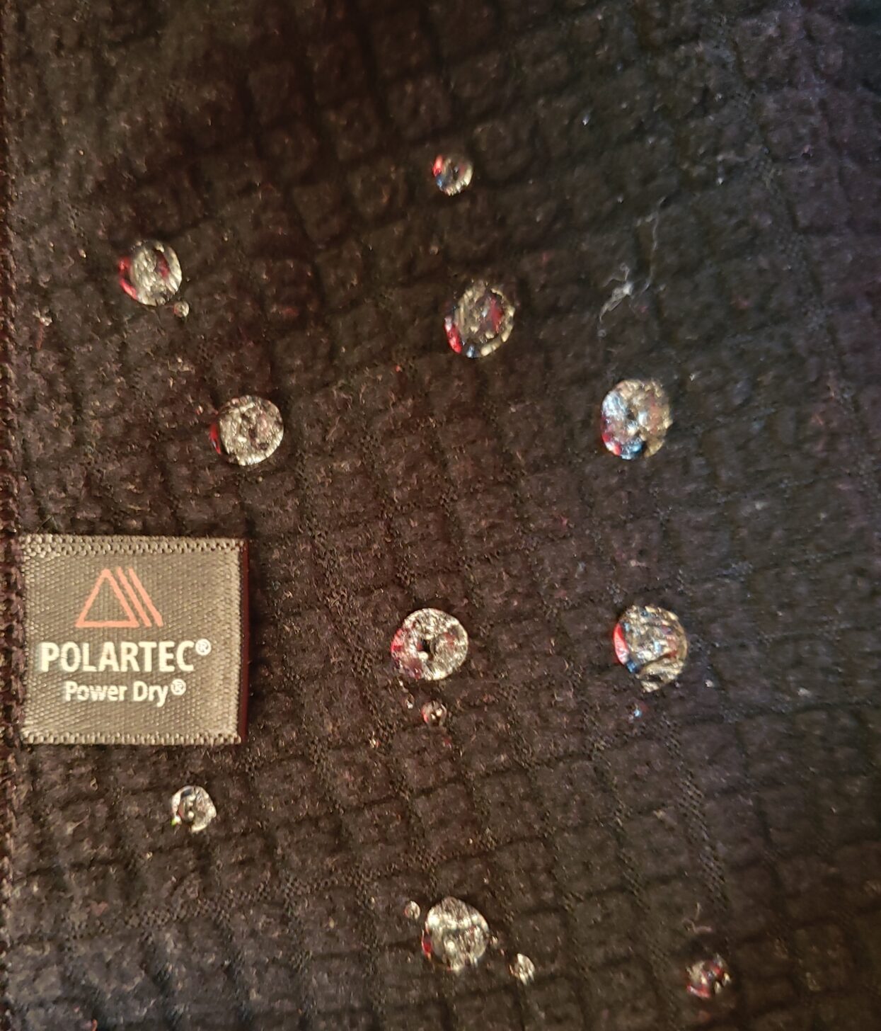 a close up of water beads on a black fabric.