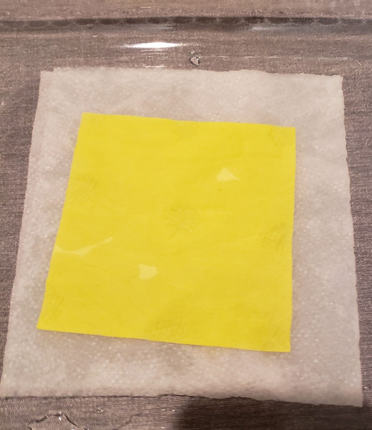 a piece of yellow fabric laying on a saturated paper towel