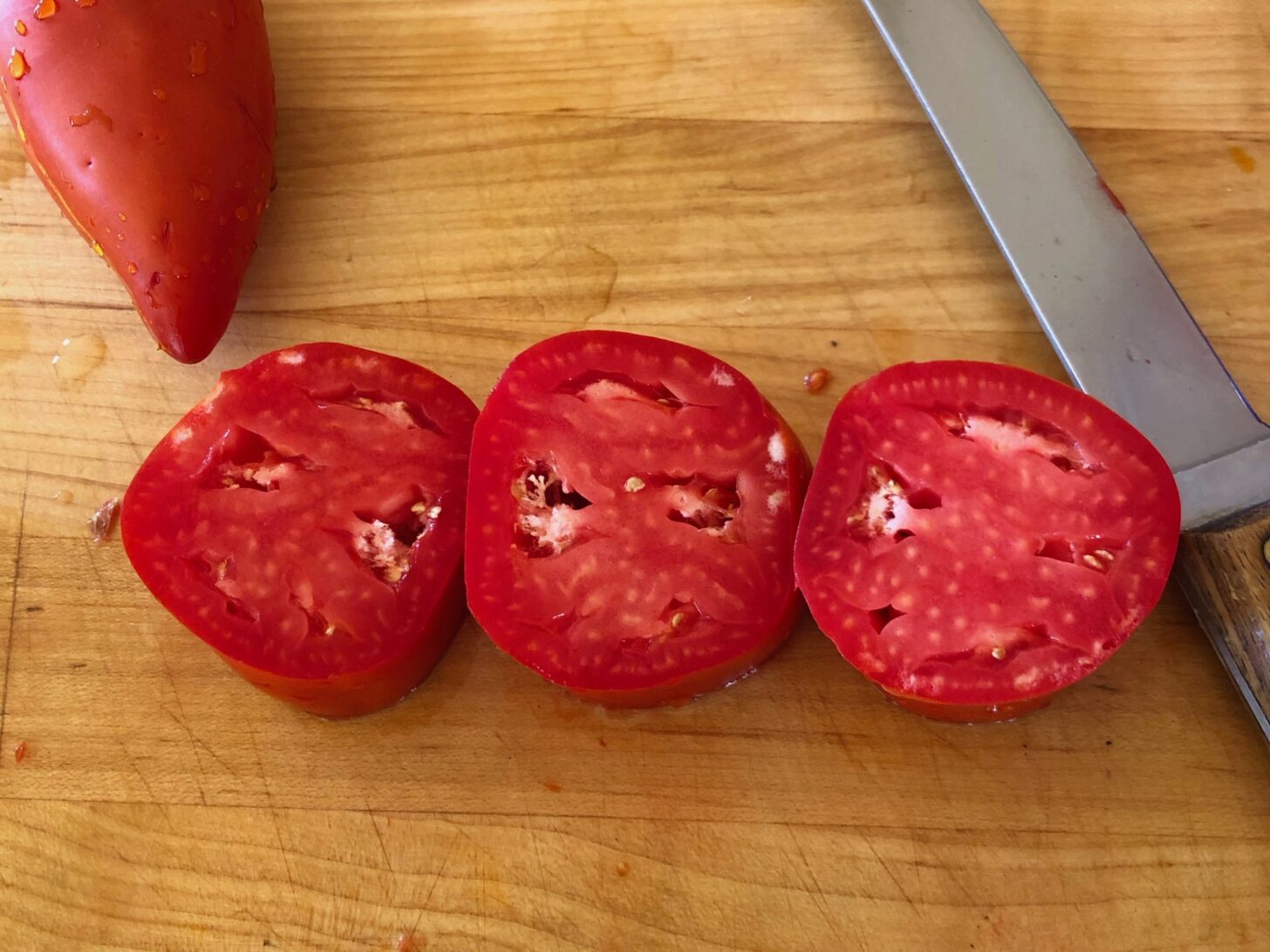 three tomato halves on a cutting board