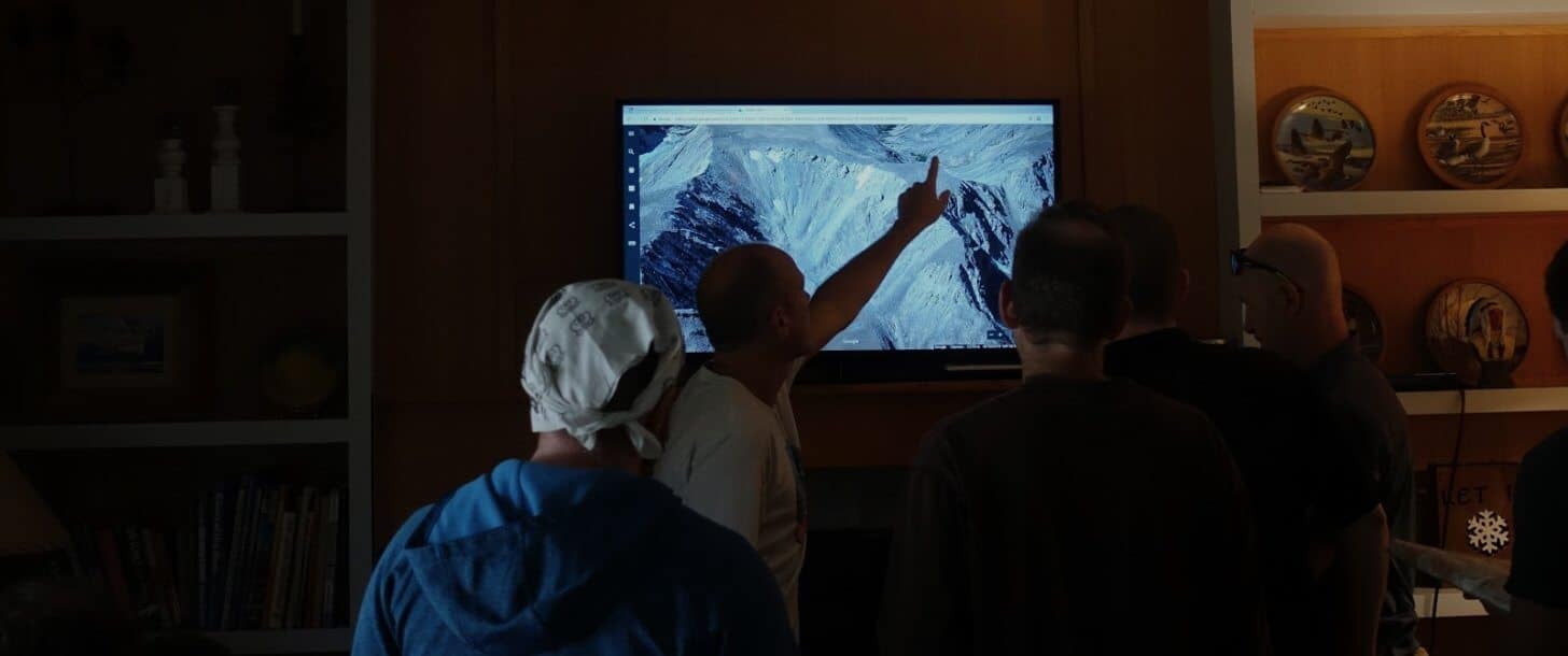 a group of people look at 3D mapping imagery on a television screen