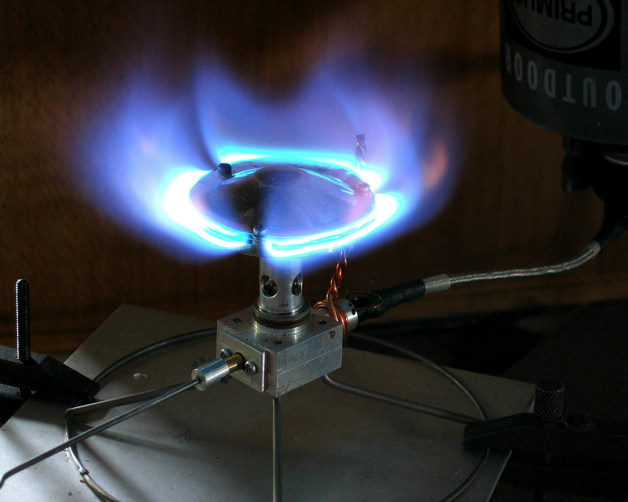 A medium shot of a stove burner head glowing brightly with blue flame