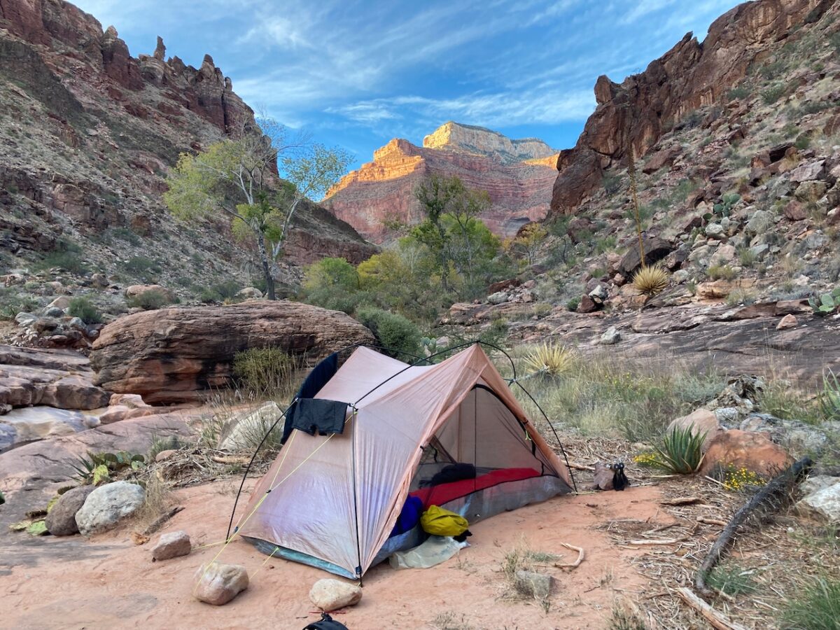 a tent is pitched in a beautiful desert canyon.