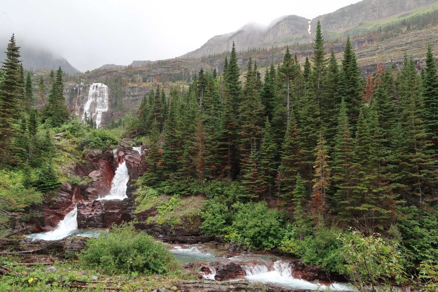 A stream cascades in the foreground with a waterfall in the background.