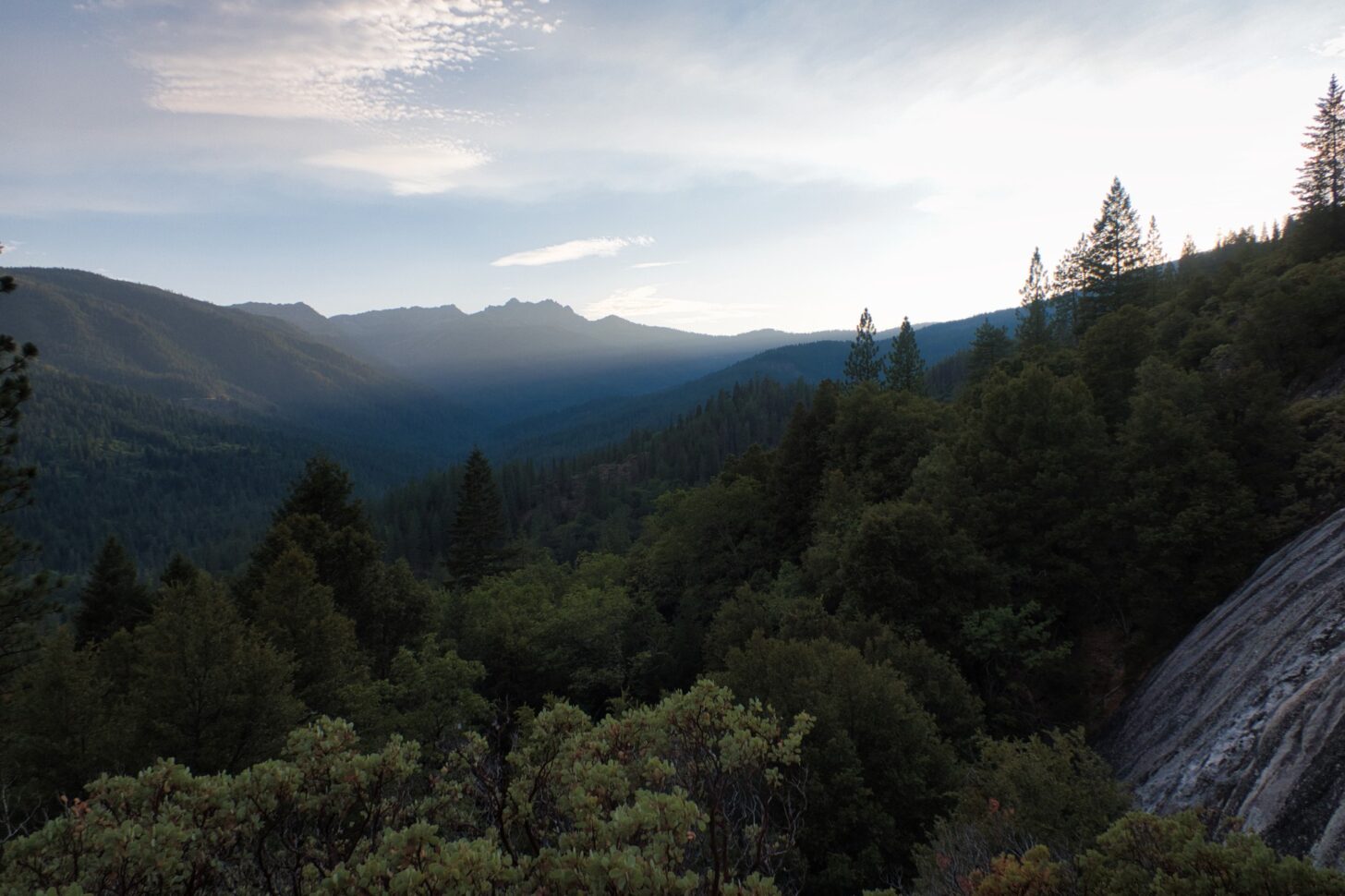 The sun sinks below a horizon of mountains.