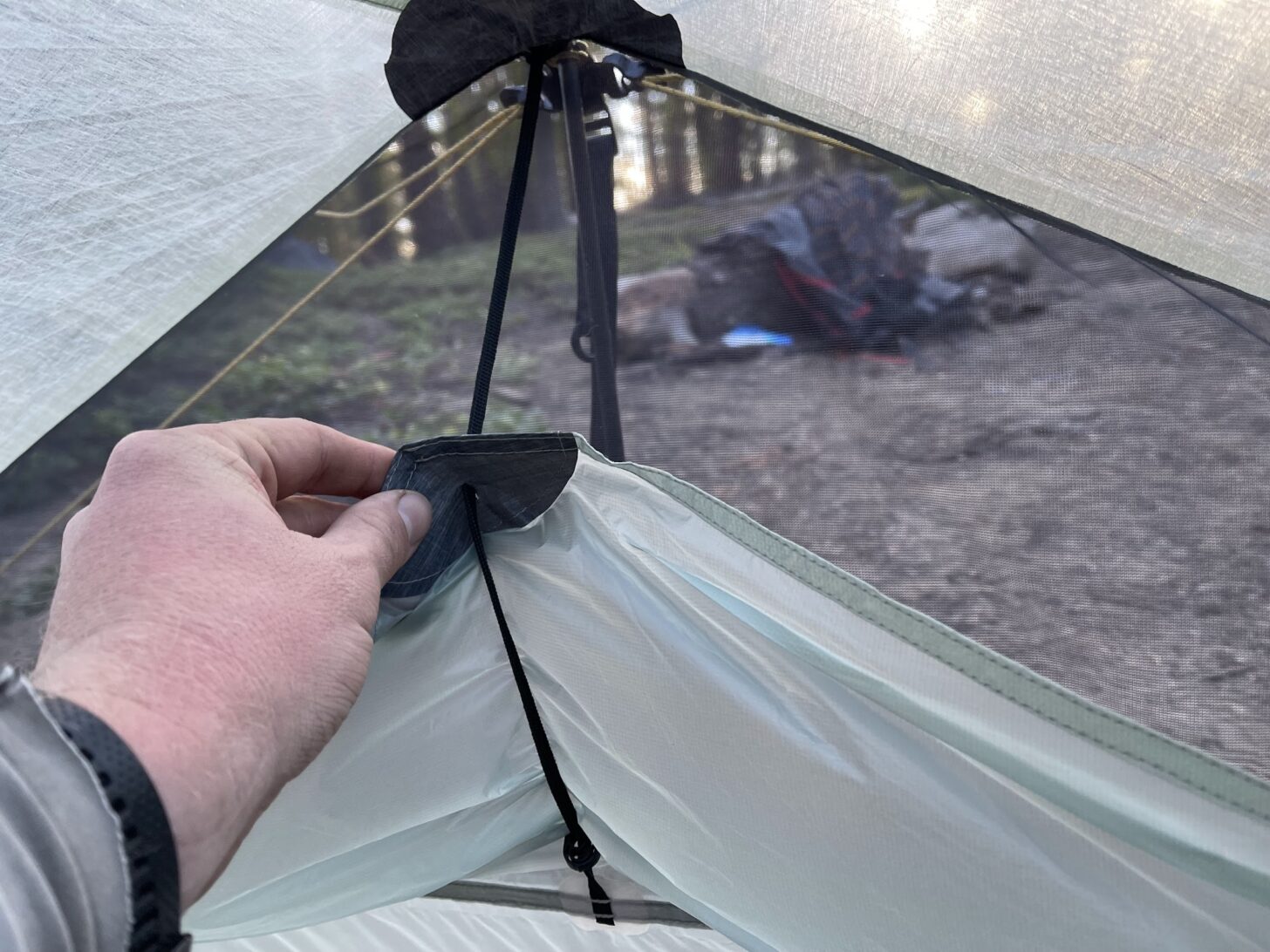 A hand pulls down the vent cover from the inside of the tent