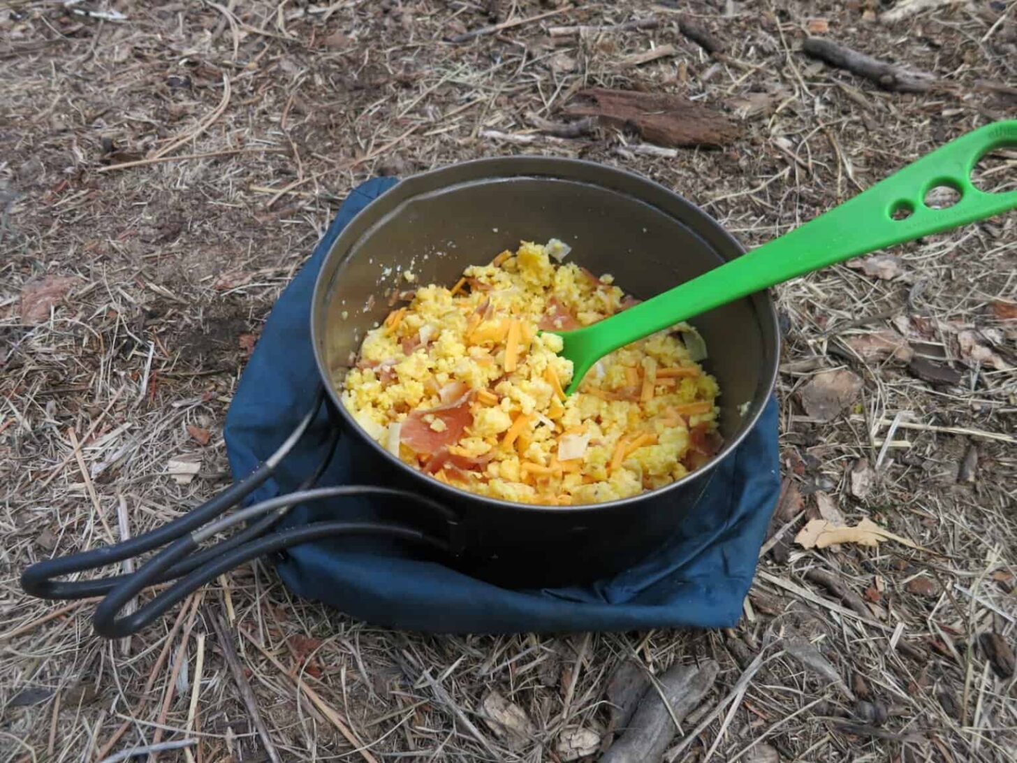 A bowl of backpacking food sitting on the ground.