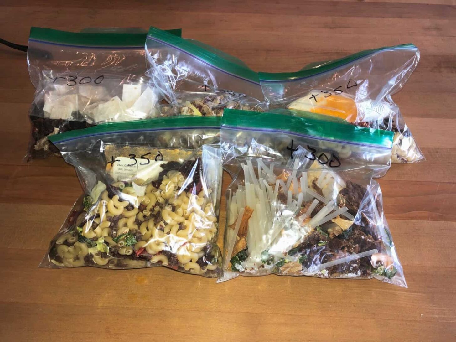 Bags of dried backpacking food sitting on a kitchen table.