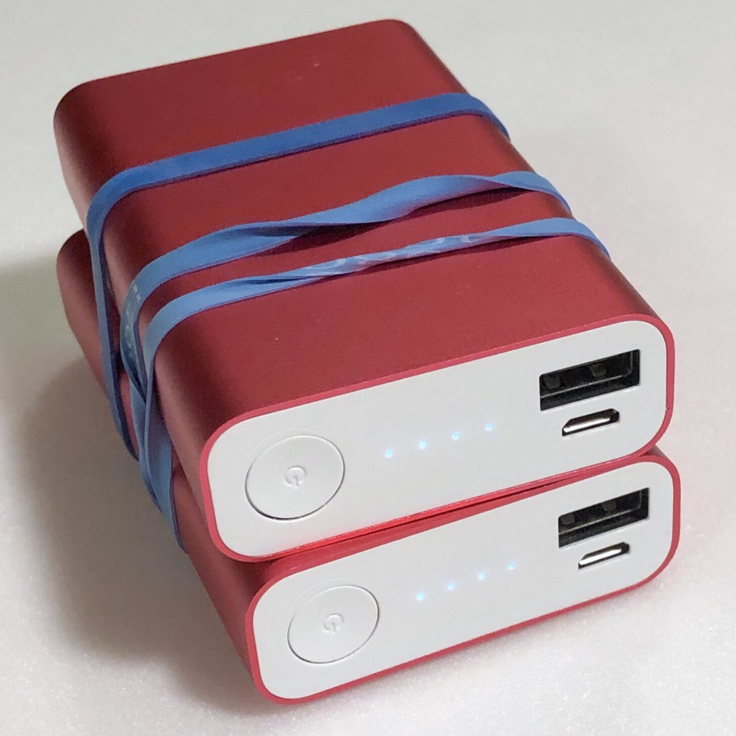 two battery packs stacked on top of each other and connected by rubber bands