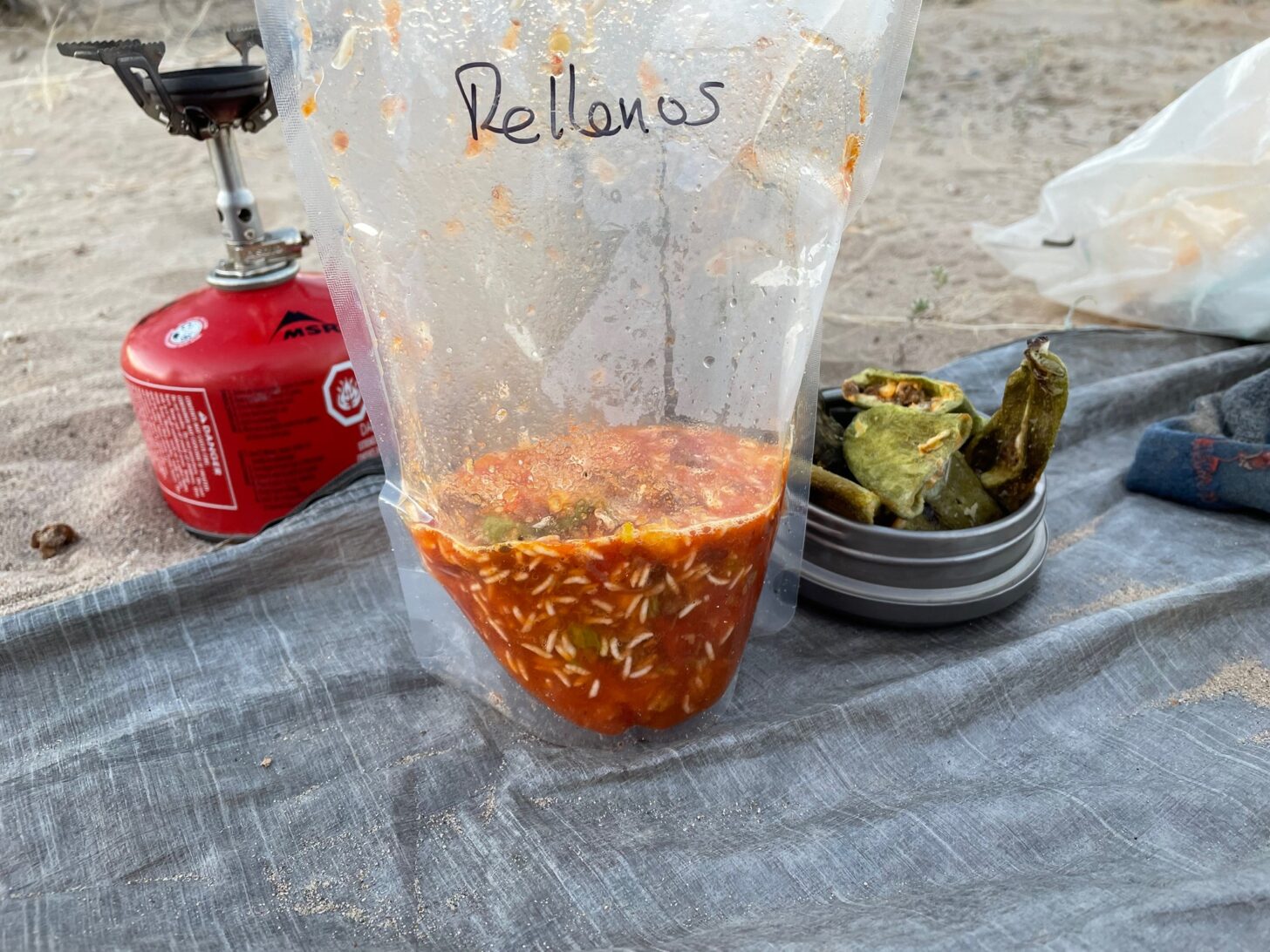 rice and sauce in a clear rehydration bag next to a bowl of freeze-dried chiles