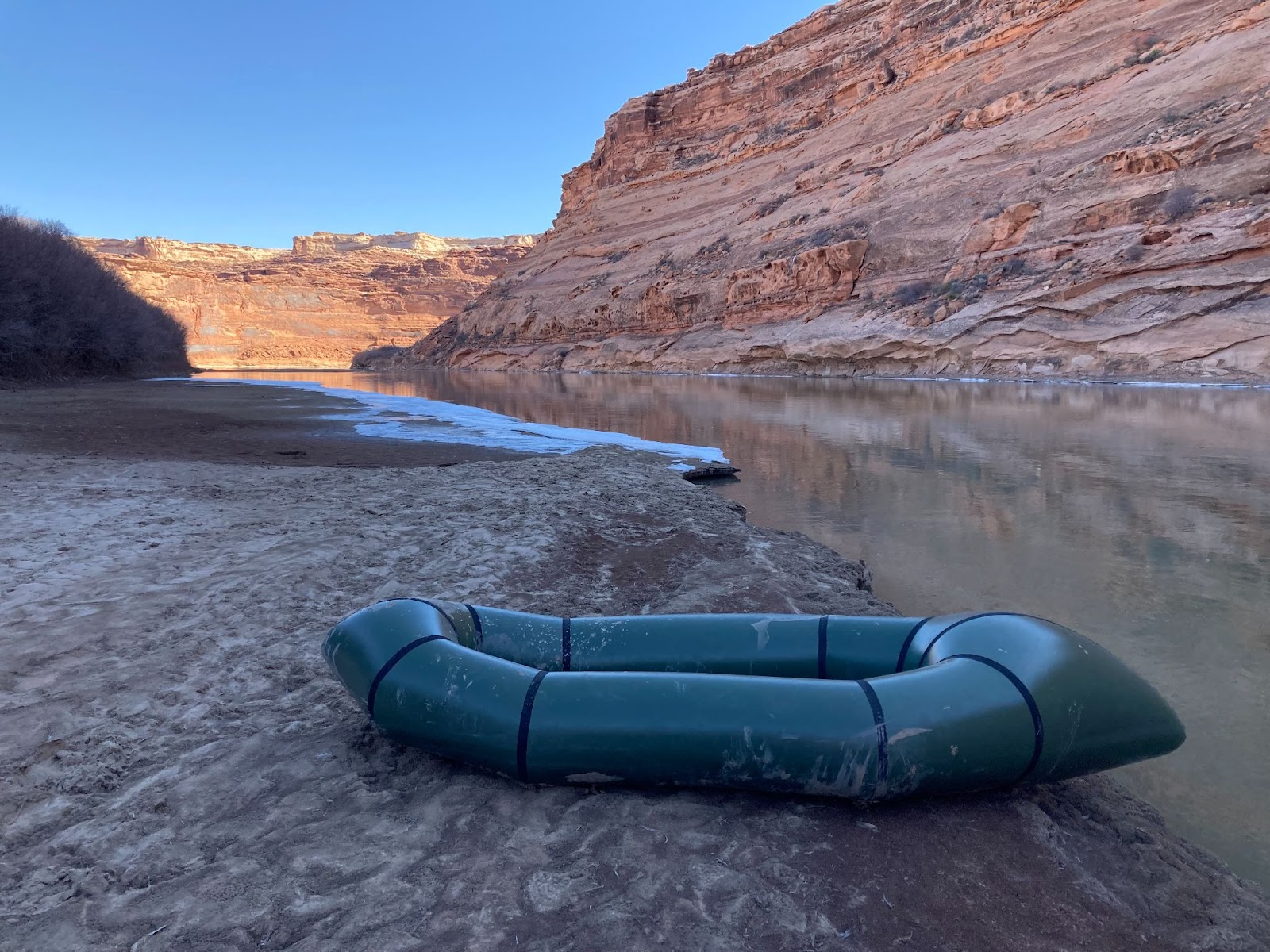 An Alpacka Scout on the shores of a river in a canyon.