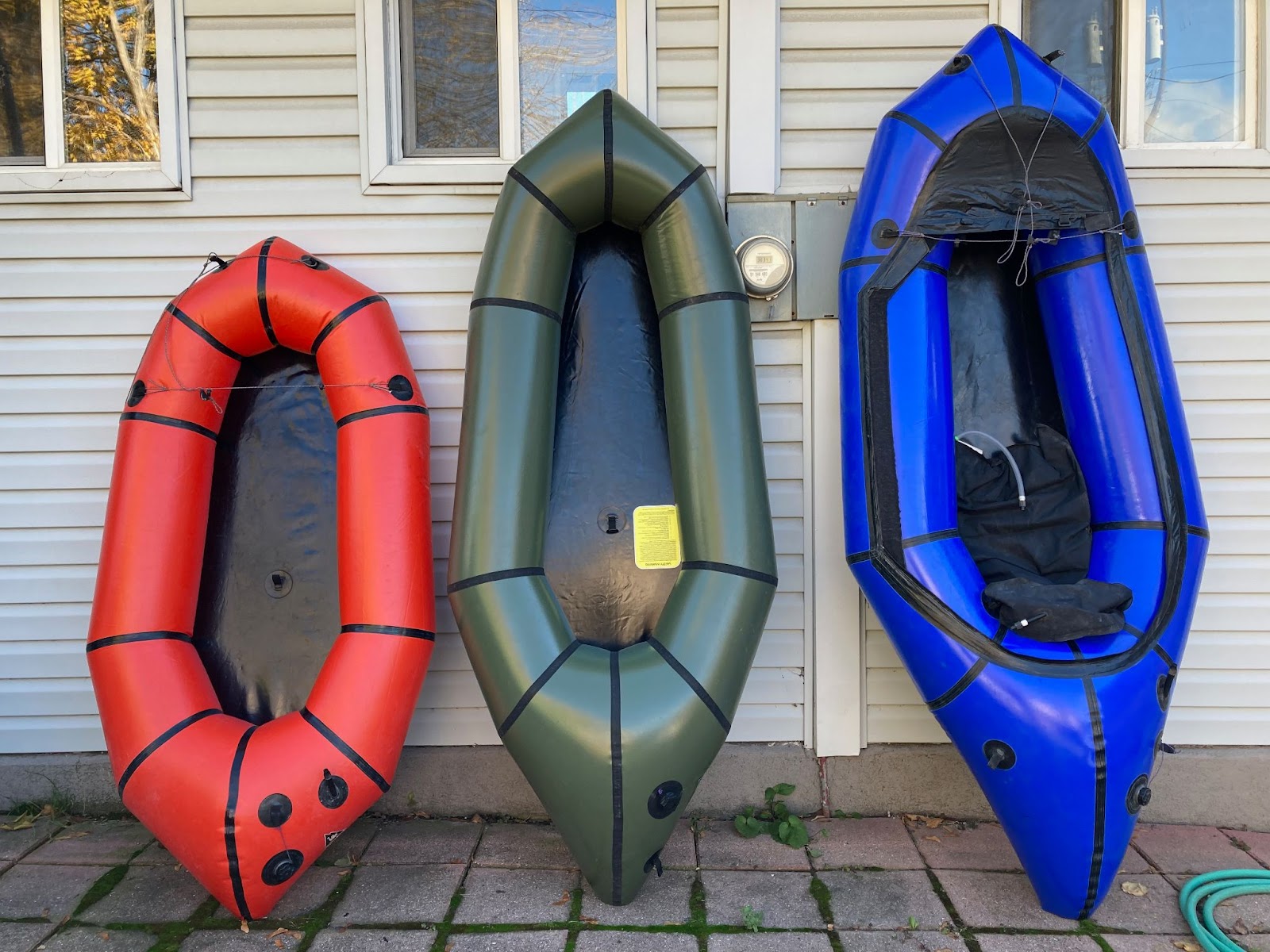 Three packrafts arranged outside on a porch. From left to right they increase in size.