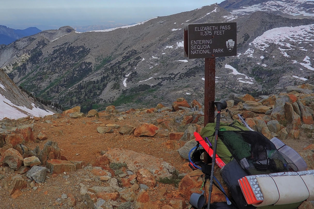 backpack lying on the ground near a sign that reads: "Elizabeth Pass, 8375 feet, Entering Sequoia National Park"