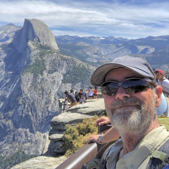 hiker wearing sunglasses with mountains in the background