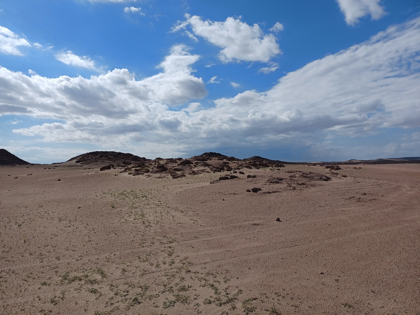 a sandy area with a few clouds in the sky