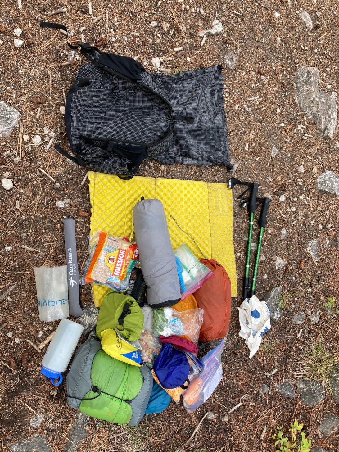 an empty pack on the ground surrounded by a pile of gear