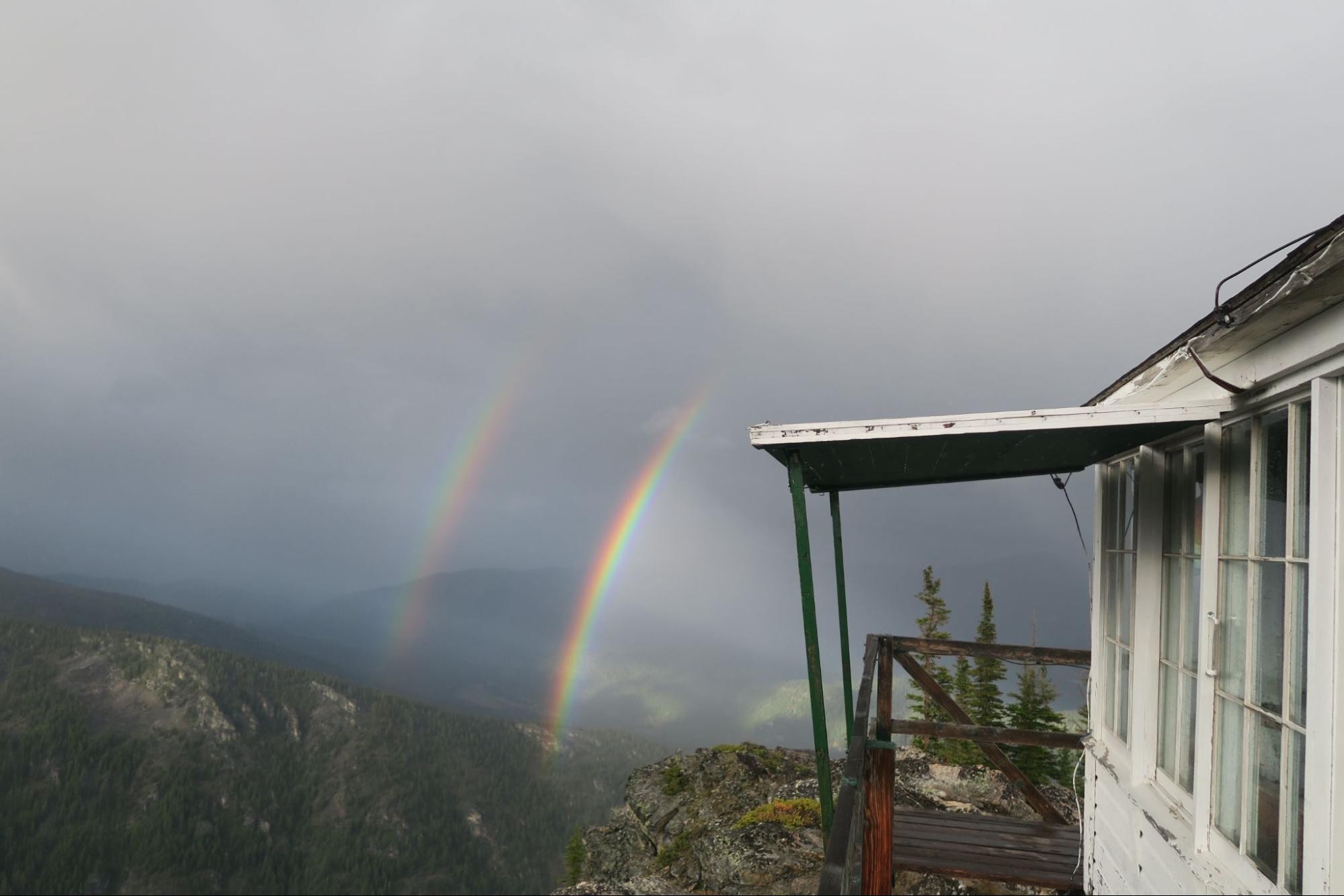 a rainbow appears over a house on a cloudy day
